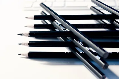 A row of sharpened black pencils on a white desk
