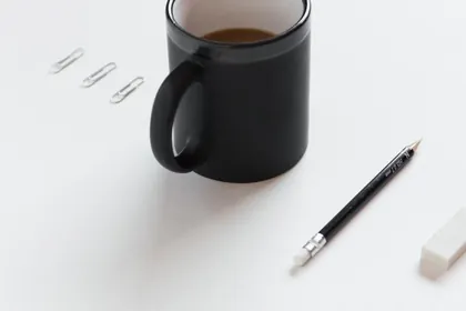 A black mug and a pencil on a white desk